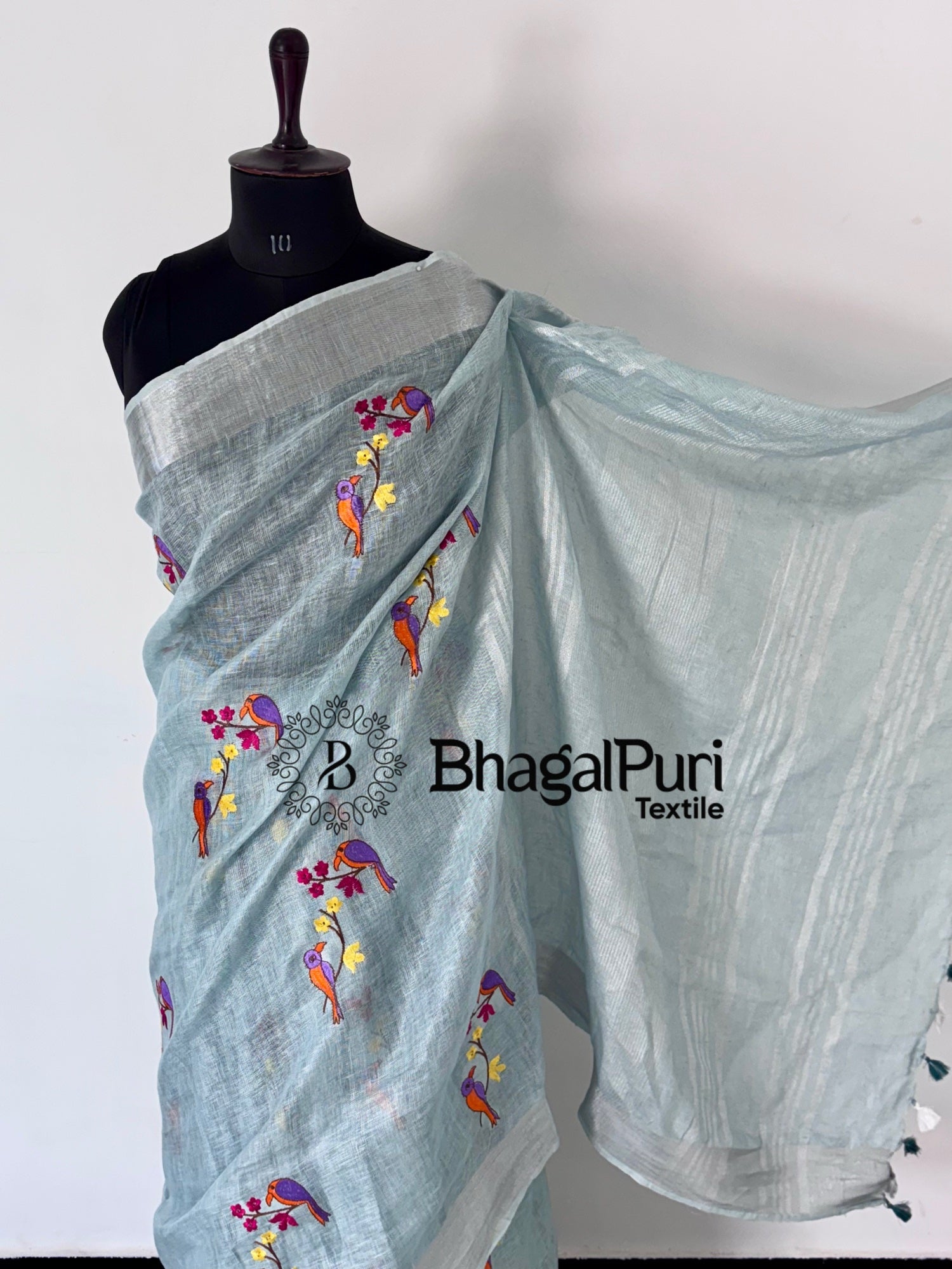 Light blue saree with floral embroidery on a mannequin, branded 'BhagalPuri Textile'.