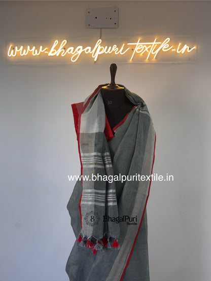 Premium ash grey linen designer saree featuring bold red piping and soft lightweight fabric.