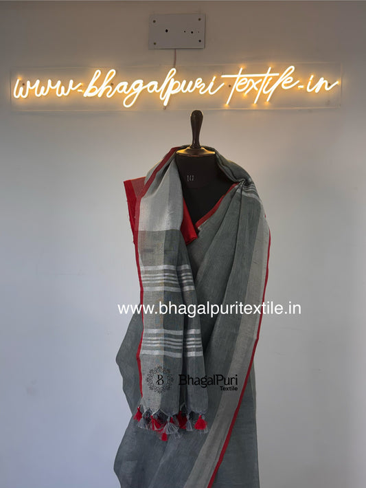 Premium ash grey linen designer saree featuring bold red piping and soft lightweight fabric.
