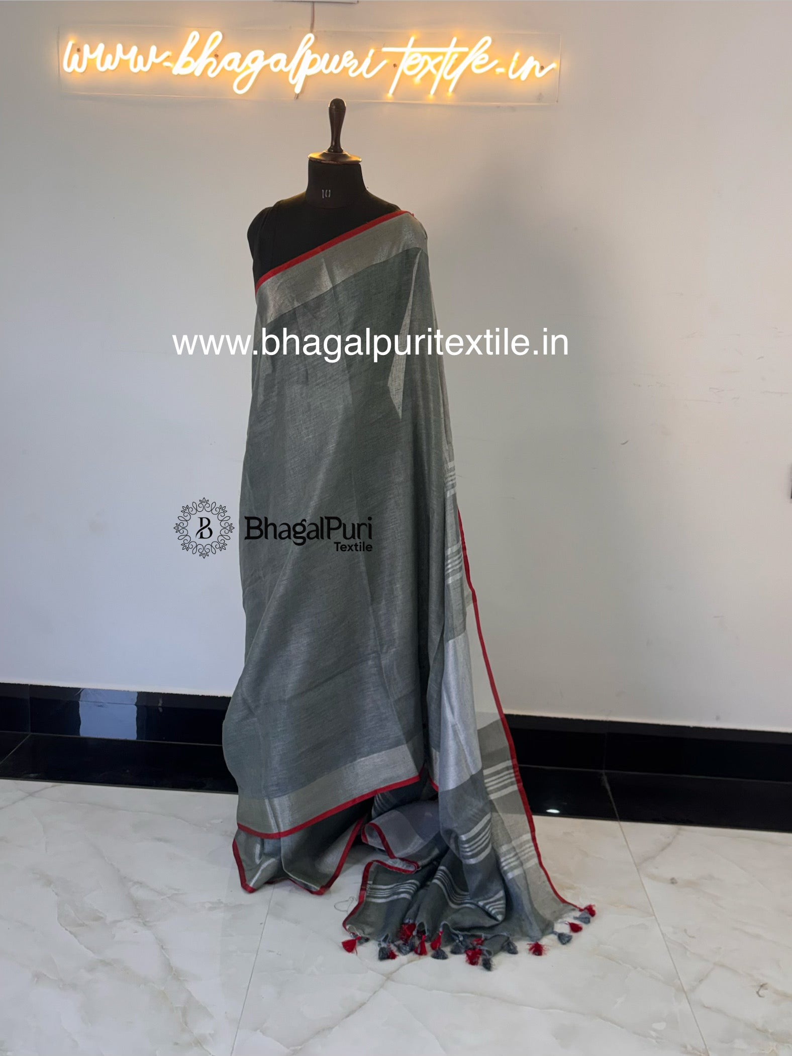 silver grey linen saree with contrast red piping border and tassel pallu for festive and party wear.