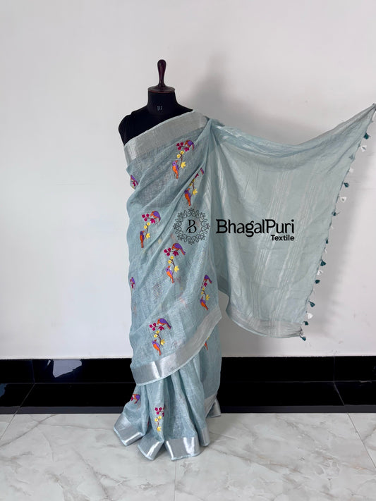 Light blue saree with floral patterns on a mannequin against a white background, branded 'BhagalPuri Textiles'.